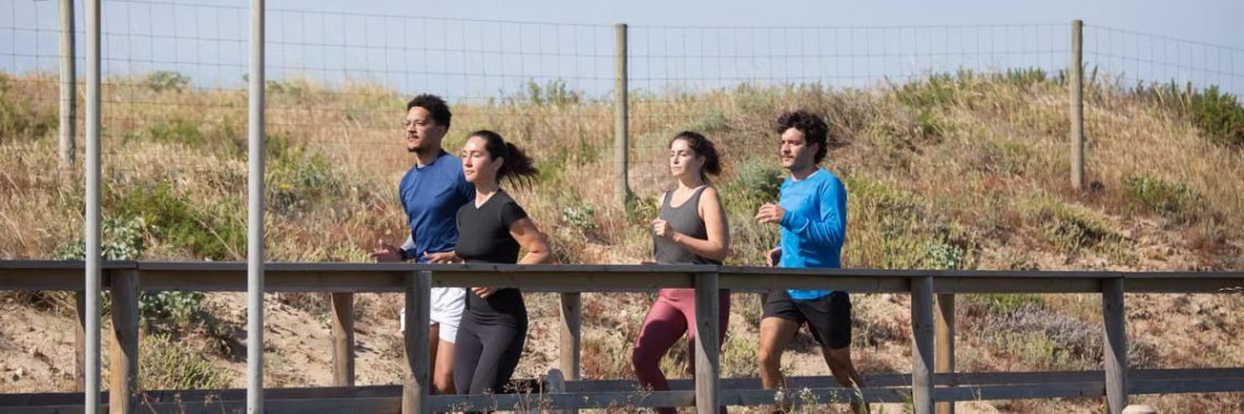 Four adults jogging on a boardwalk in Portugal, promoting a healthy lifestyle.